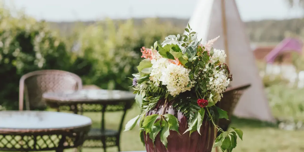 Un hermoso arreglo de flores en un jarrón morado, perfecto para celebrar un feliz día del Carmen.