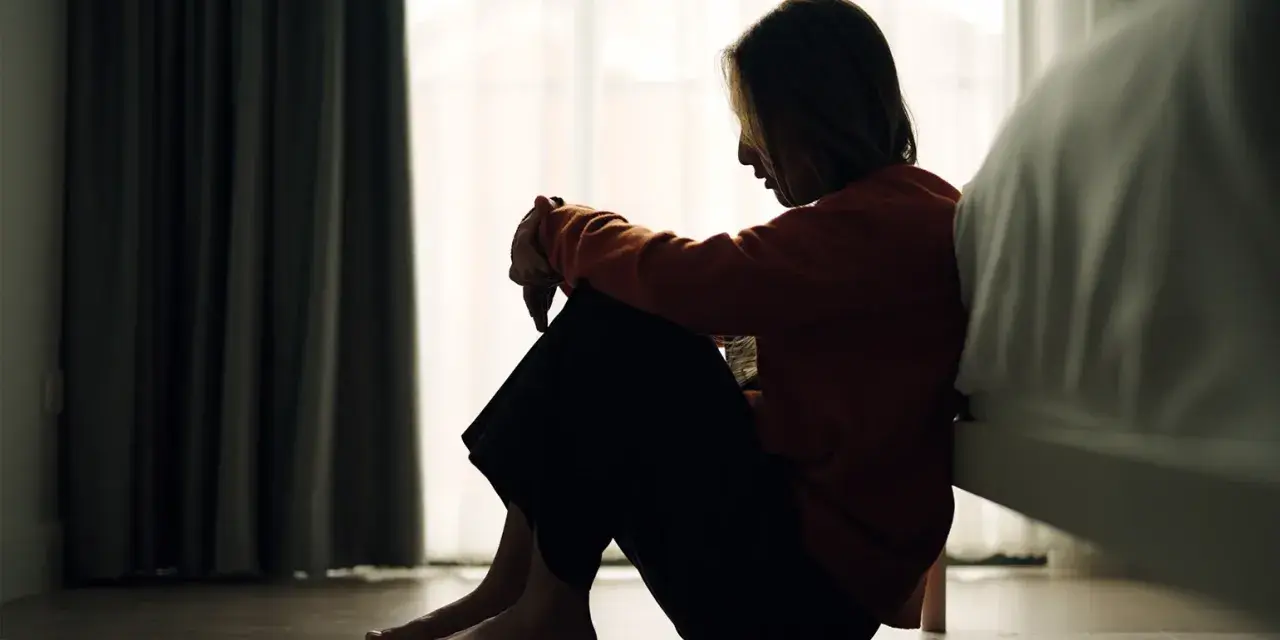 Ein Mädchen sitzt traurig auf dem Boden, die Knie angezogen. Die Szene könnte die emotionale Achterbahnfahrt bei borderline bei Kindern darstellen.