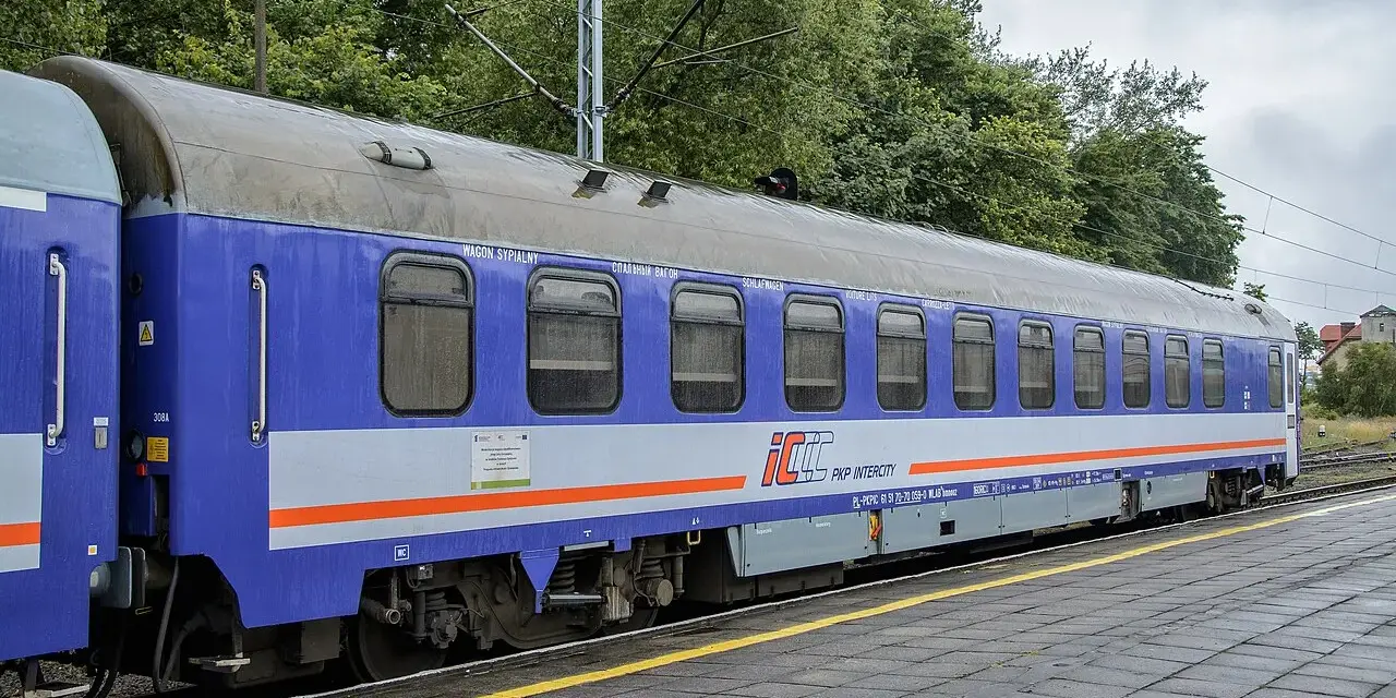 Niebiesko-szary wagon sypialny PKP Intercity stoi na torach. Wygodny przedział sypialny PKP zaprasza do podróży.