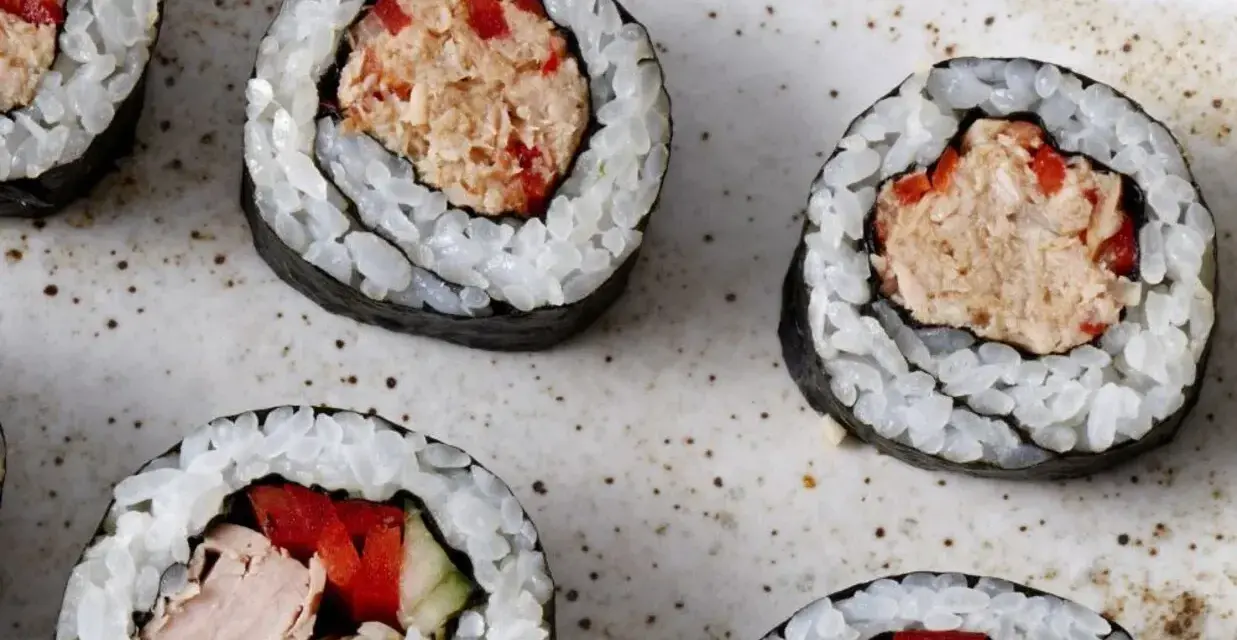 Kilka kawałków sushi z tuńczykiem i warzywami na talerzu.