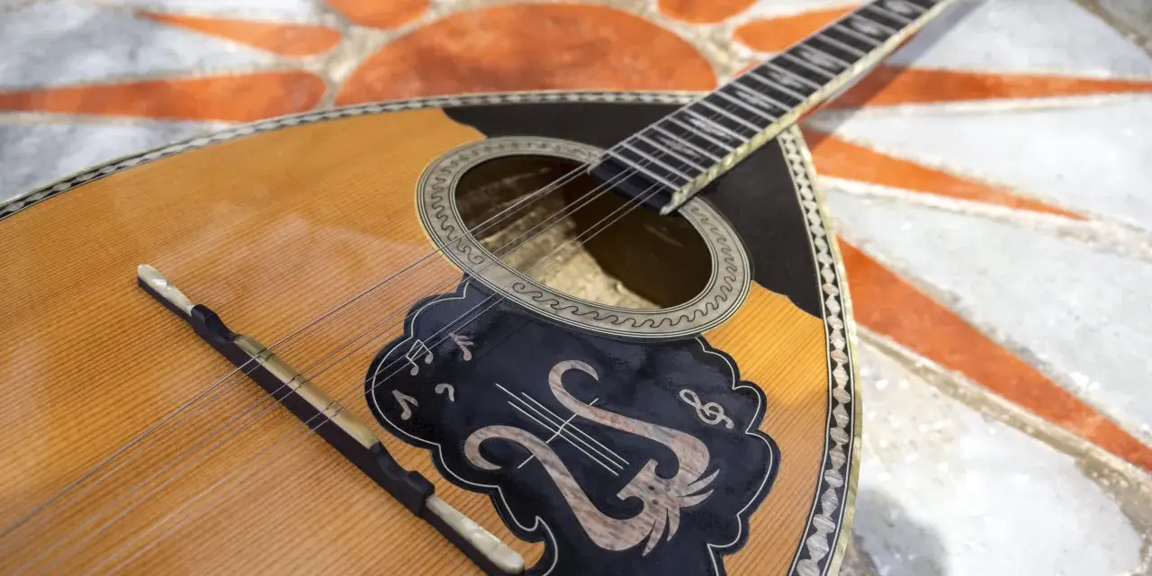 Piękny grecki instrument muzyczny, bouzouki, leży na mozaice z symbolem słońca.