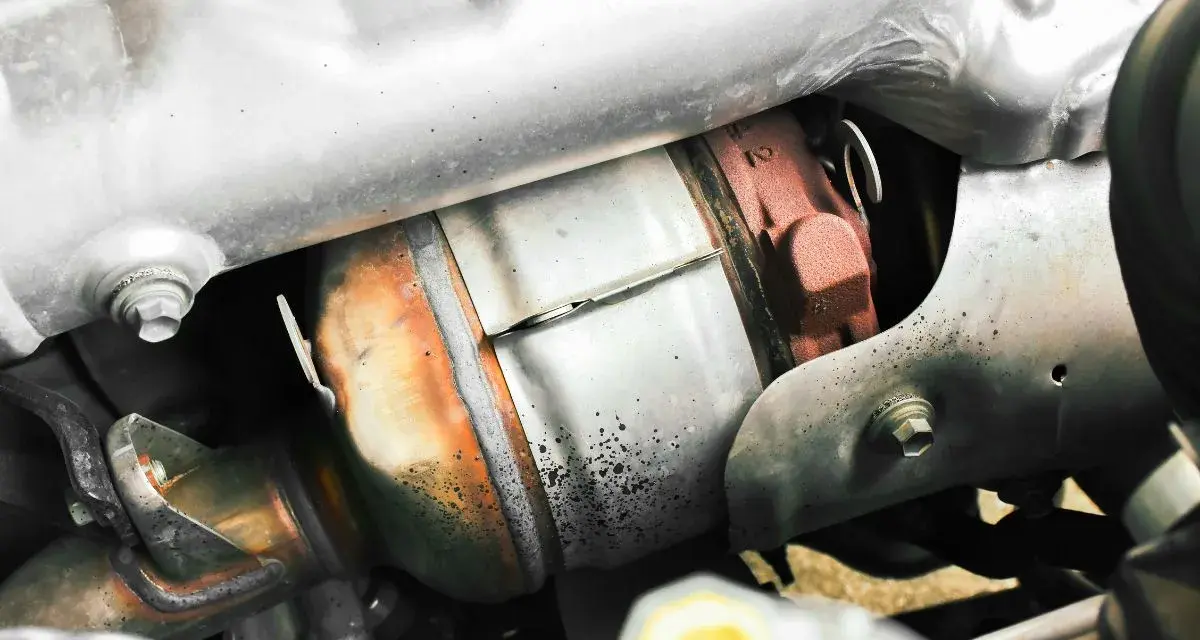 Dettaglio del sistema di scarico di un'auto, con il filtro antiparticolato (FAP) visibile. Togliere il FAP vantaggi: meno intasamenti, migliore fluidità dei gas.