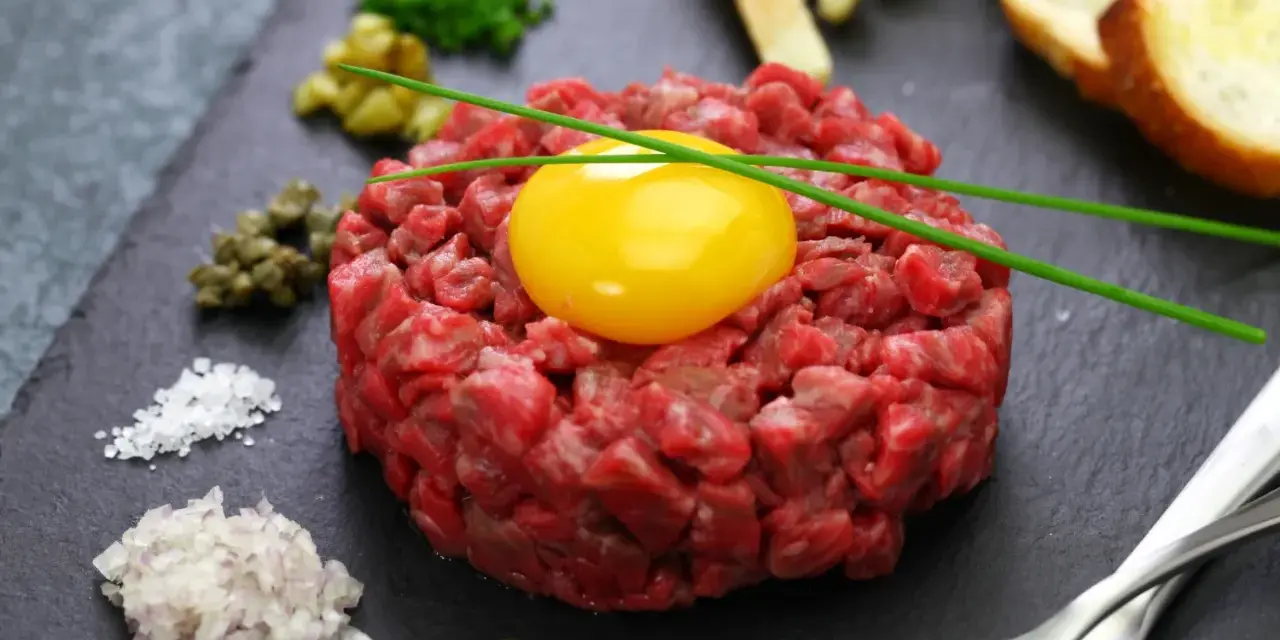 Tartare di manzo fresca e succulenta, con tuorlo d'uovo, capperi, cipolla, sale, pepe e crostini.