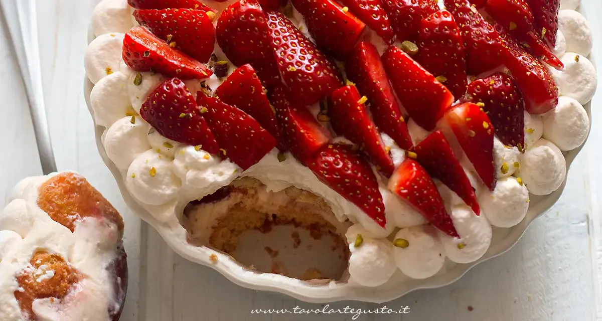 Delizioso tiramisù alle fragole, con panna montata, fragole fresche e pistacchi tritati. Una fetta è già stata servita.