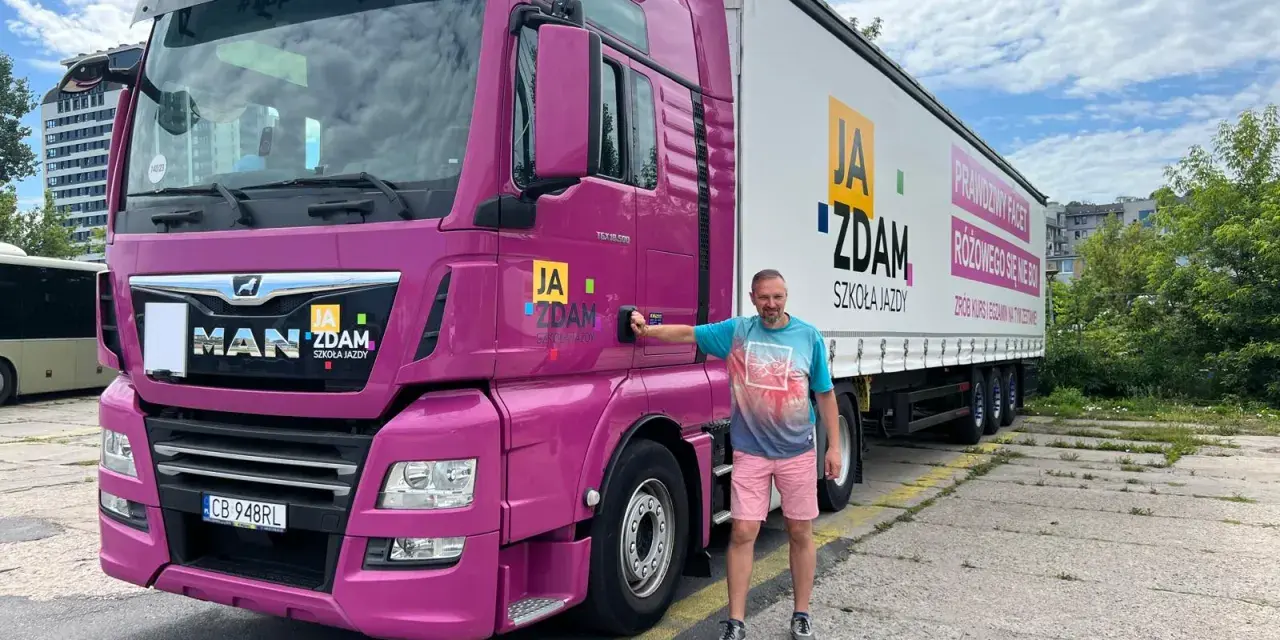 Mężczyzna obok różowej ciężarówki MAN. Na naczepie napis "JA ZDAM SZKOŁA JAZDY". Dowiedz się, ile kosztuje prawo jazdy C.