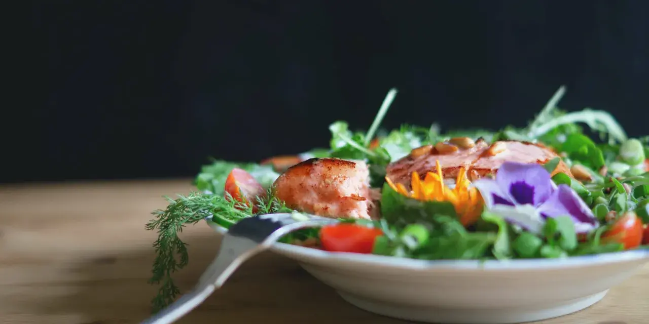 En vacker sallad med lax, tomater och ätbara blommor. Perfekt för att deffa mat och njuta av en hälsosam måltid.