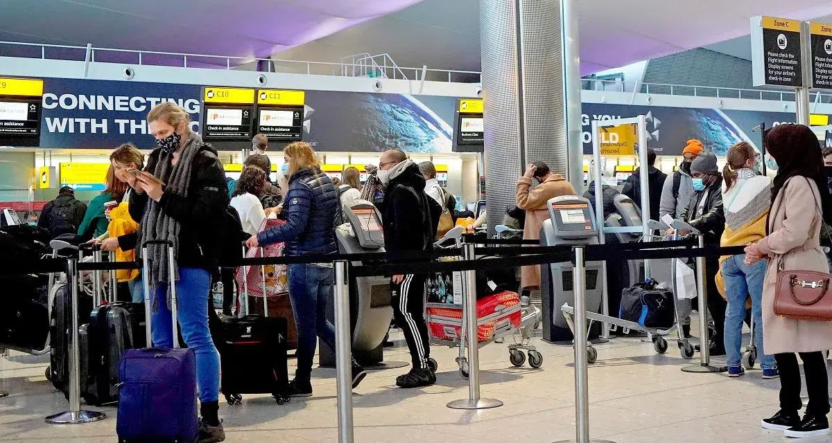 Kolejka do odprawy na lotnisku, przypominająca terenową delegaturę paszportową w Bielsku-Białej. Ludzie z bagażami czekają na swoją kolej.