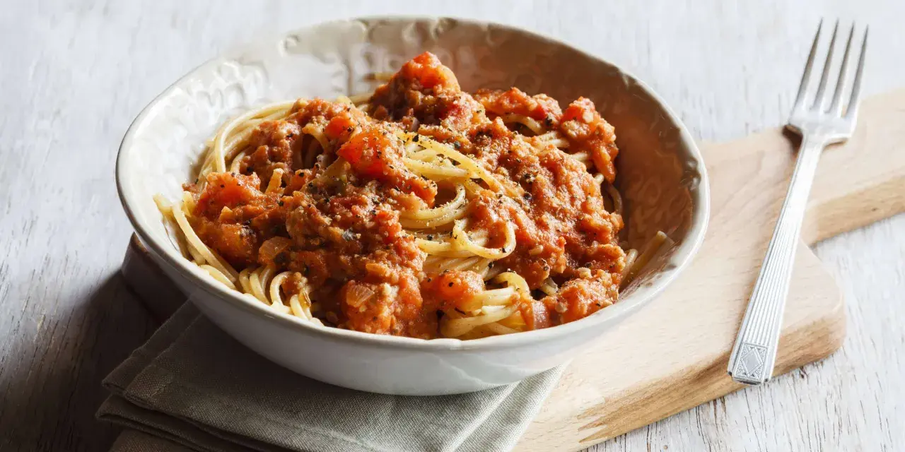 Eine Schüssel Spaghetti mit einer herzhaften, tomatigen Bolognese-Sauce, perfekt für eine schnelle Mahlzeit.