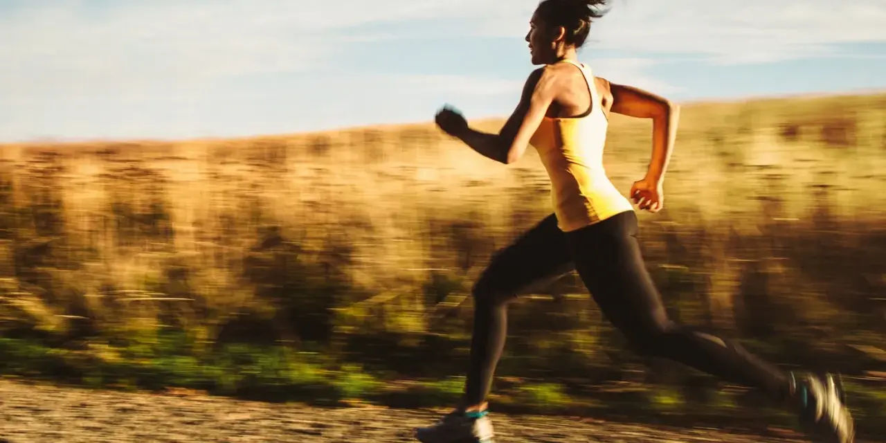 Kvinna springer i full fart, ett intensivt hiit pass utomhus.