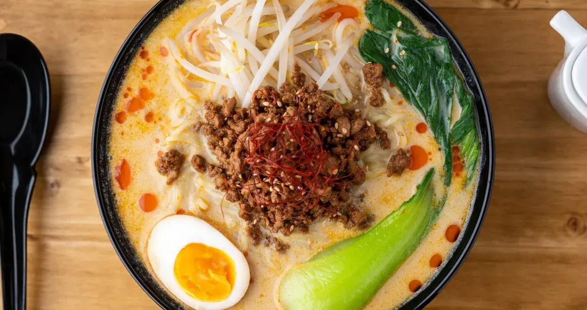 Miseczka ramenu tantanmen z mielonym mięsem, jajkiem, kiełkami i warzywami.