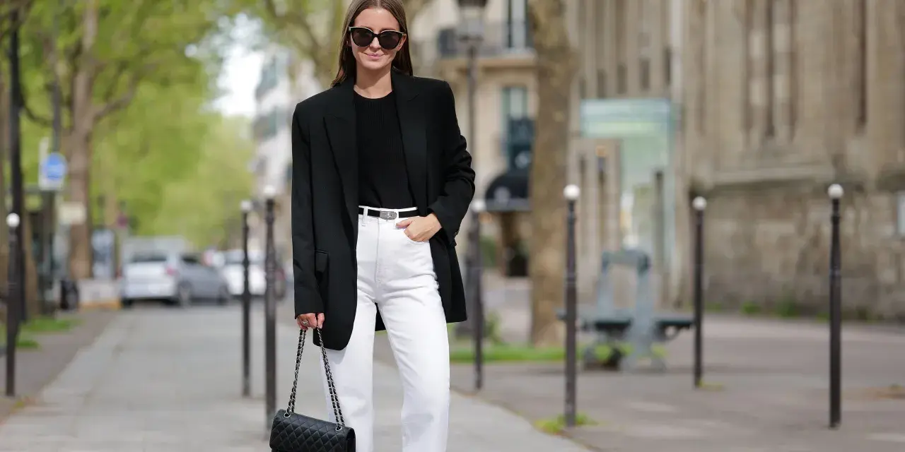 Donna con blazer nero, jeans bianchi e borsa Chanel, un look che aiuta a sembrare più alto.
