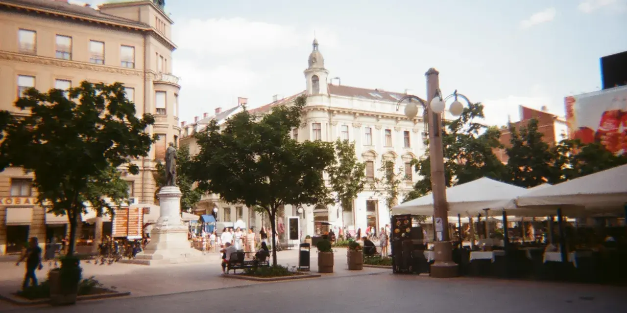 Spacer z kawiarnianymi stolikami i ludźmi, uchwycony aparatem Kodak M35.