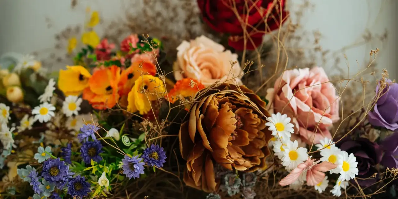 Un ramo de flores secas y artificiales, con tonos ocres, rosas, naranjas y morados. Una guía visual sobre como preservar flores para un recuerdo eterno.