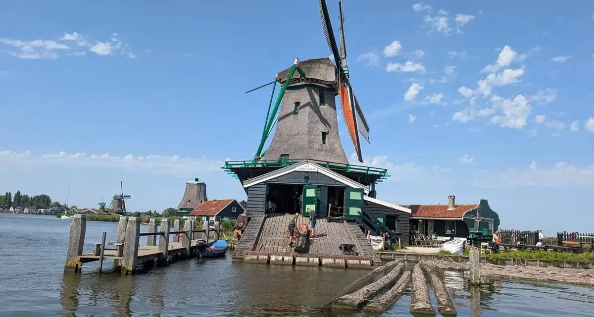 Wiatraki w Zaanse Schans nad wodą, z drewnianym pomostem i łódkami.