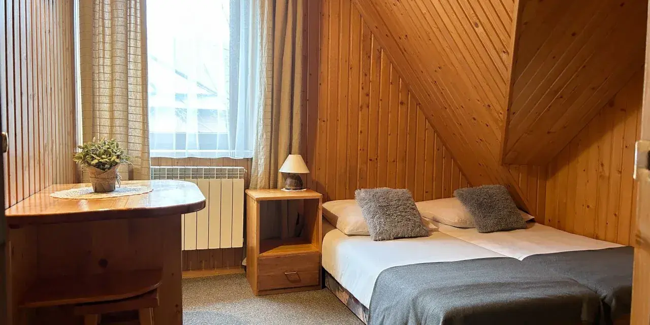Pokój w stylu góralskim, idealny na wypoczynek u Lucyny Białka Tatrzańska. Dwa łóżka, drewniane meble i przytulna atmosfera.