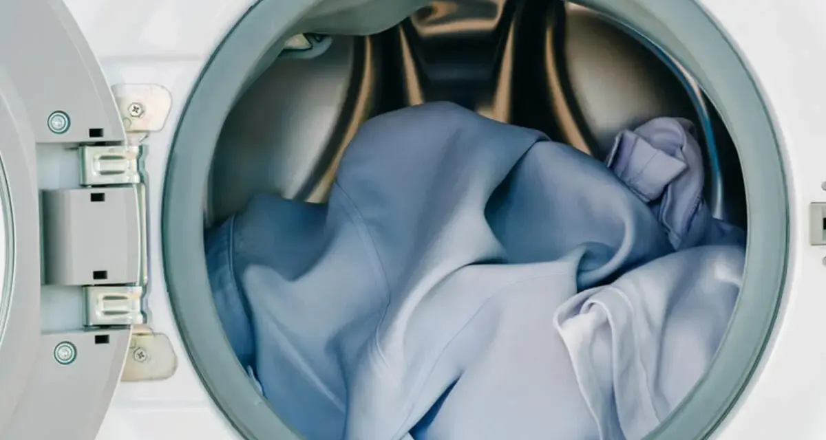 Blaue Wäsche in einer offenen Waschmaschine. Die Frage, ob Polyester einlaufen kann, beschäftigt viele.