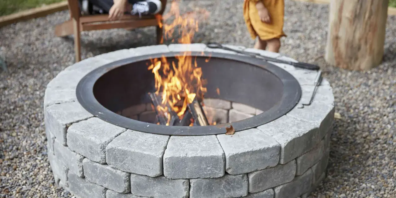 A stone fire pit with a roaring fire, perfect for a backyard gathering. This image shows how to build a fire pit for cozy evenings.
