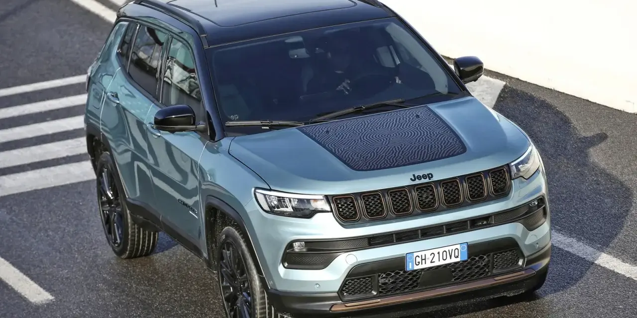 Jeep Compass color acqua con tetto nero, su strada con strisce bianche. La pressione pneumatici è ottimale per affrontare ogni percorso.