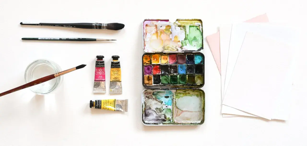 Matériel d'artiste : palette de peinture, tubes de couleur, pinceaux et papier pour le support aquarelle.
