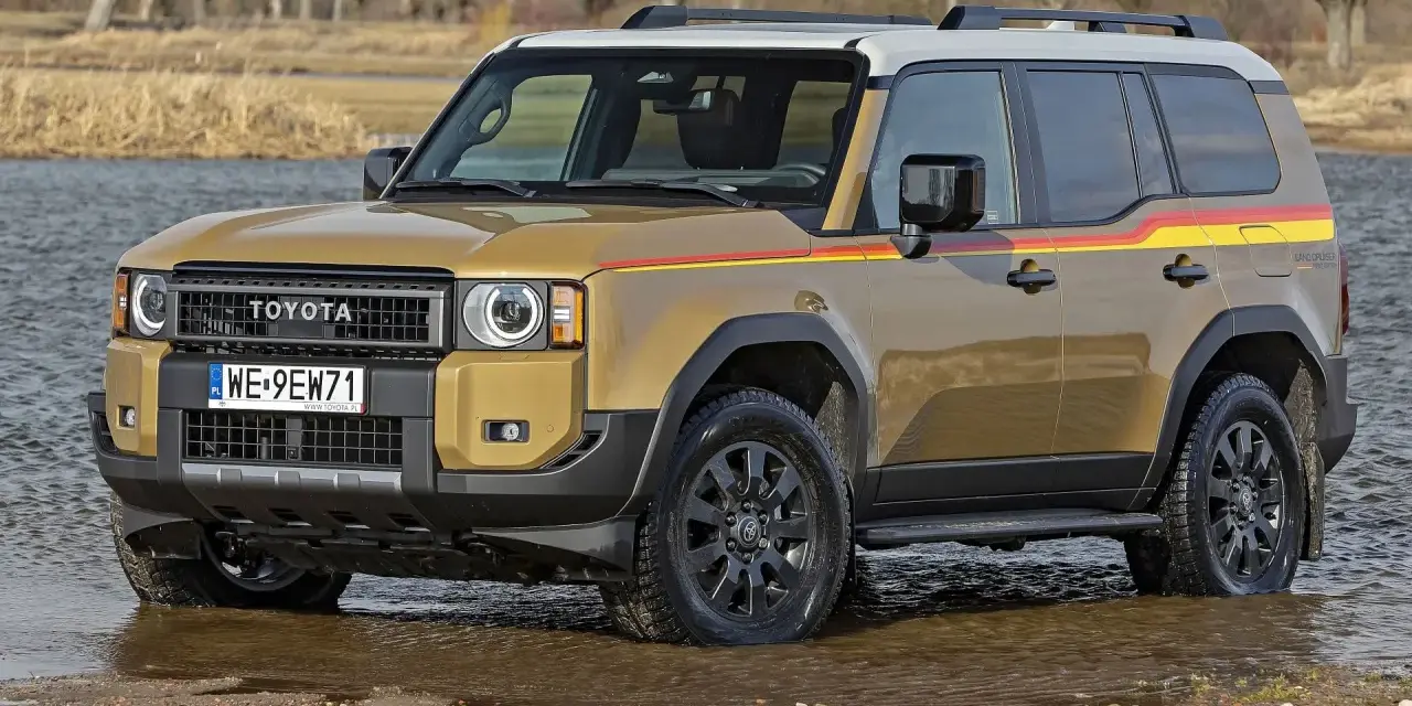 Złoty Toyota Land Cruiser Prado z kolorowymi pasami na boku, wjeżdża do wody.