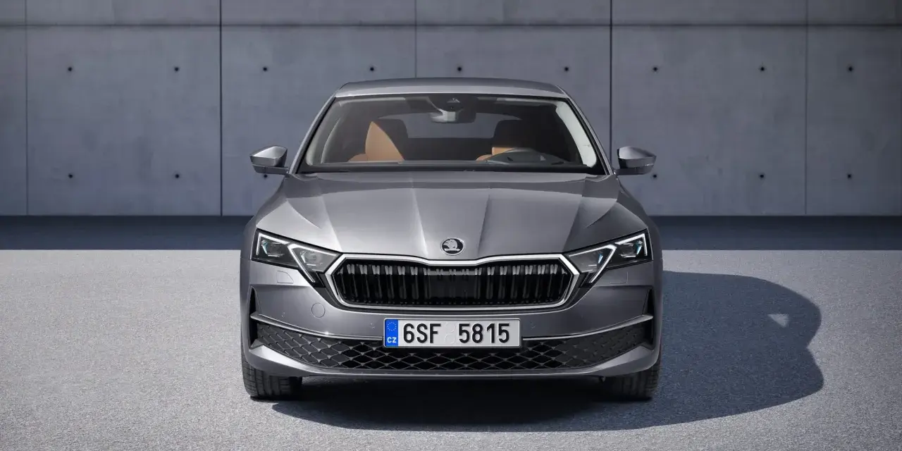 Nowa Skoda Octavia w szarym kolorze, z brązowym wnętrzem, prezentuje się elegancko na tle betonowej ściany.
