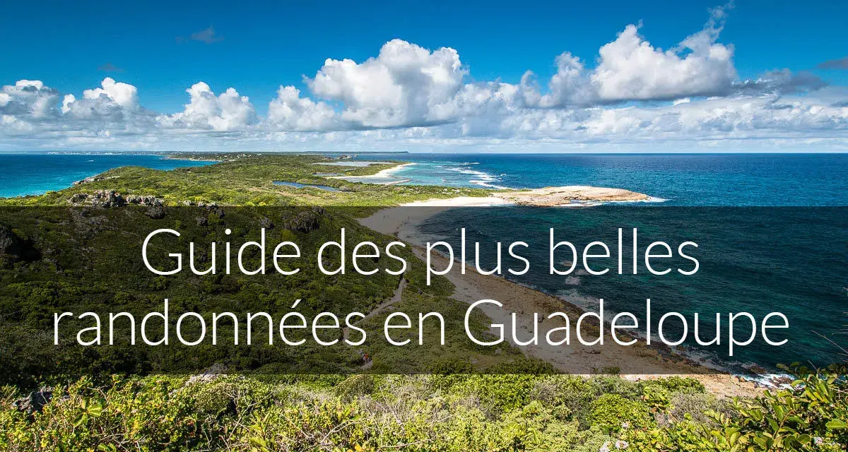 Paysage côtier luxuriant avec la mer bleue et des nuages blancs. Ce guide des plus belles randonnées en Guadeloupe vous invite à explorer ses montagnes verdoyantes.