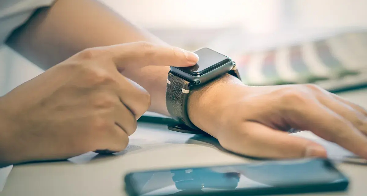 Dłoń z zegarkiem na nadgarstku, palec dotyka ekranu, pokazując jak włączyć bluetooth w smartwatch.