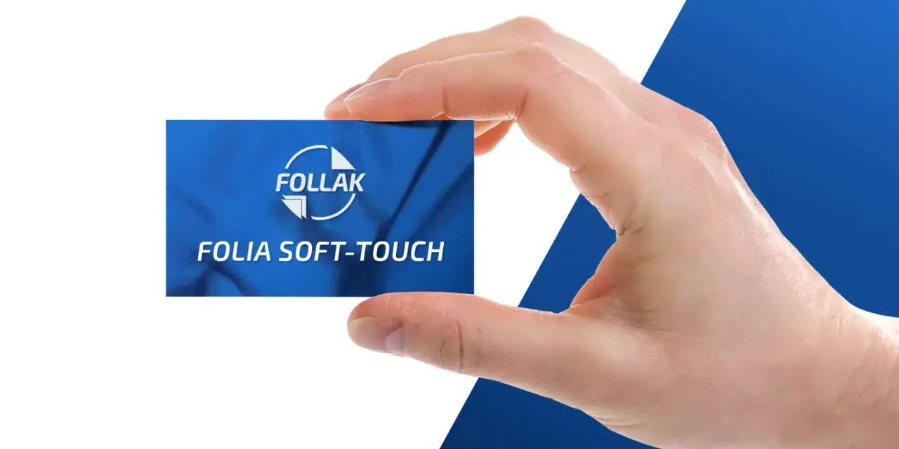 Dłoń trzyma kartę z napisem "Folia Soft-Touch" od FOLLAK, prezentując efekt laminacji.