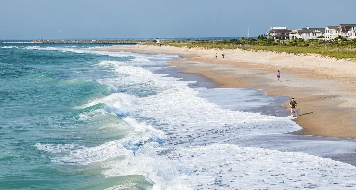 Waves crash on the shore at Wrightsville Beach, where people enjoy a run and a stroll, showcasing some of the relaxing things to do.