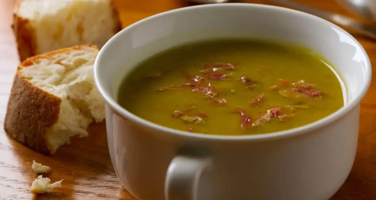 Un bol de soupe de pois cassés fumante, garnie de lardons, avec du pain croustillant à côté. Un délice réconfortant.