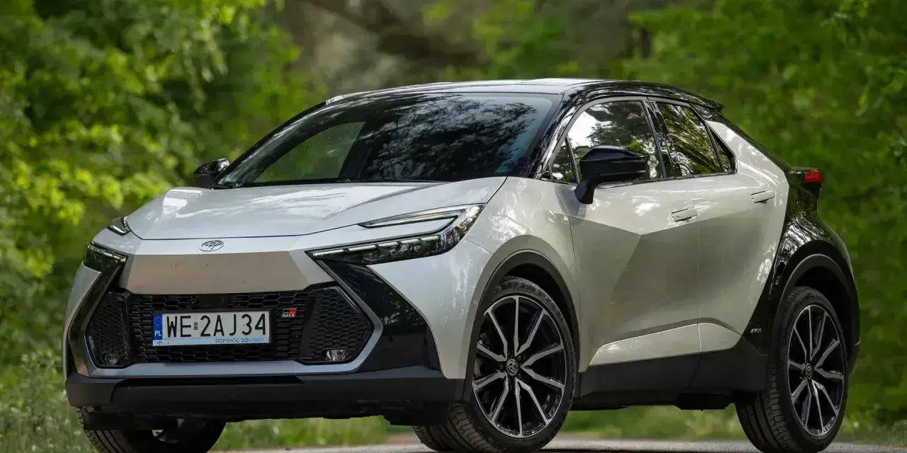 Nowy Toyota C-HR Hybrid w kolorze srebrno-czarnym na tle zieleni.
