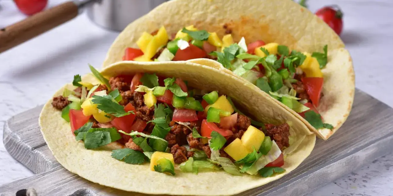 Dwa pyszne, domowe fast foody: tortille z mielonym mięsem, pomidorami, papryką, mango i świeżą kolendrą.