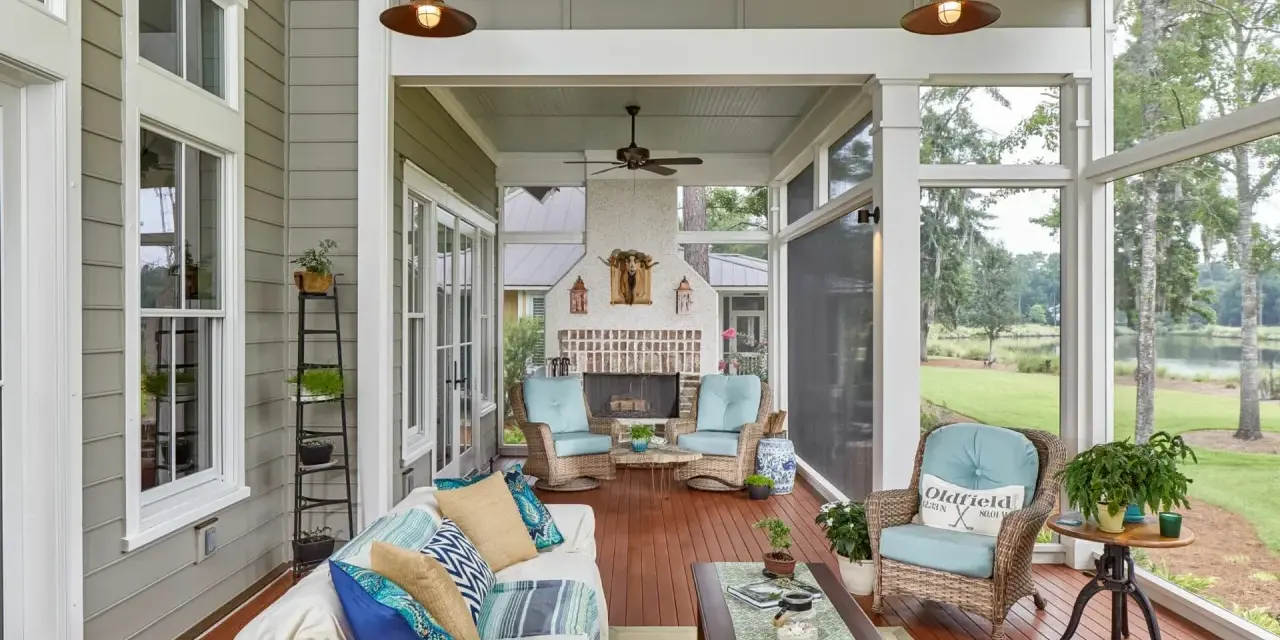 A cozy screened-in patio with a fireplace, wicker chairs, and a sofa, perfect for enjoying the view of the lake.