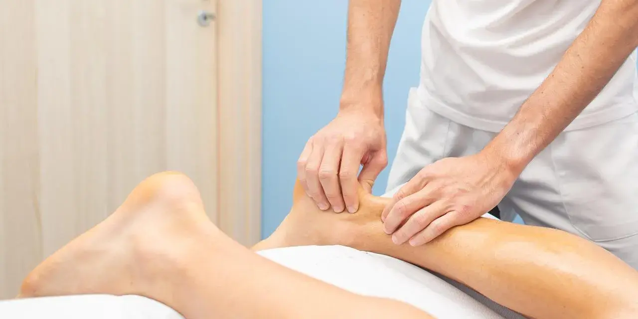 Physiotherapeut behandelt Achillessehne Schmerzen mit einer Massage am Unterschenkel.