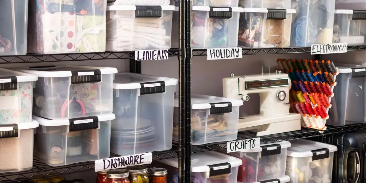 Organized basement storage ideas with labeled clear bins for linens, holiday items, crafts, electronics, and dishware.
