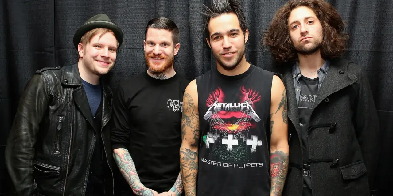 Czterech mężczyzn z zespołu Fall Out Boy pozuje do zdjęcia na tle czarnej kurtyny.