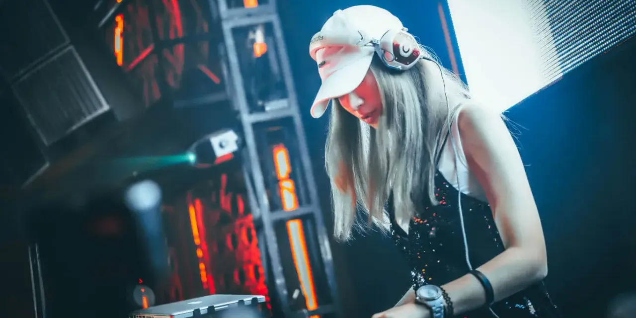 DJane legt auf, die Menge tanzt zu fetter electro dance music. Rote Lichter blitzen, die Musik pulsiert.