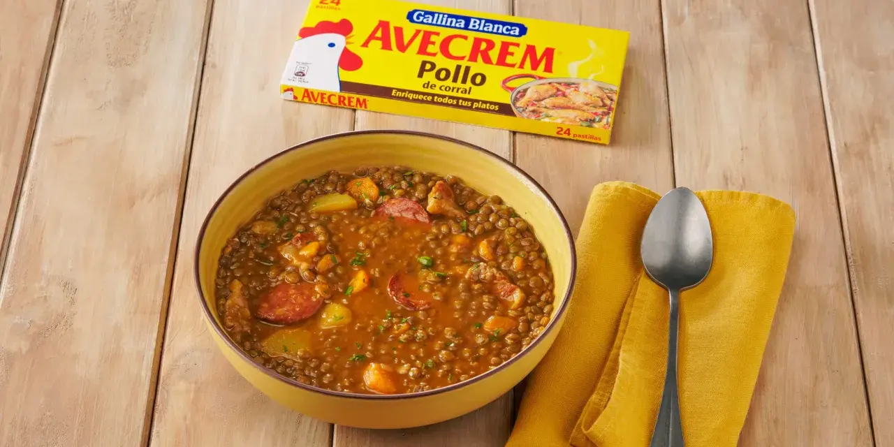 Un tazón de lentejas estofadas con chorizo y patatas, junto a un paquete de Avecrem Pollo.