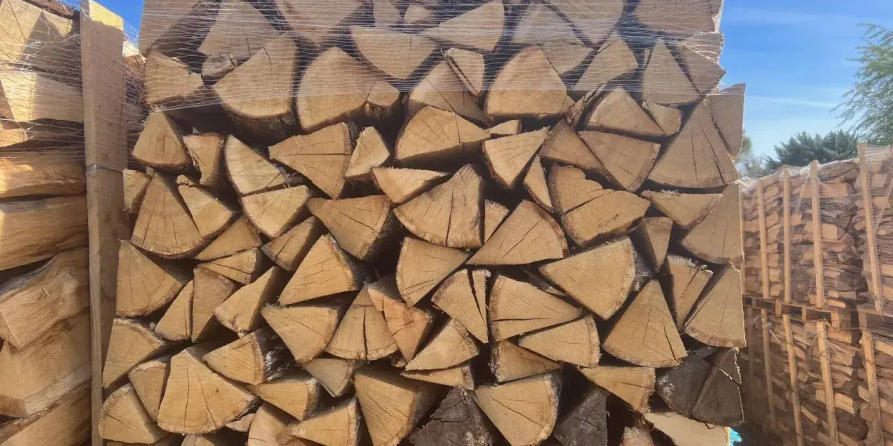 Un grand stère de bois, bien empilé et emballé sous plastique, prêt pour l'hiver.