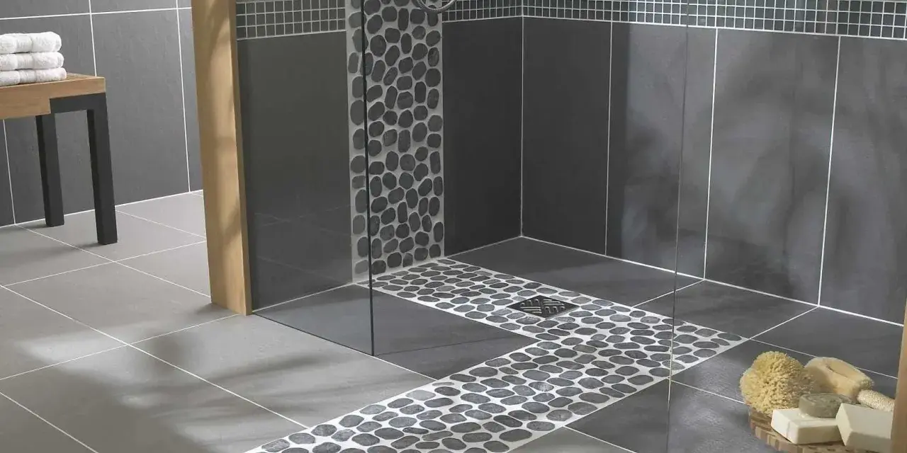 Carrelage moderne avec un chemin de galets sur le receveur de douche, créant une ambiance zen.