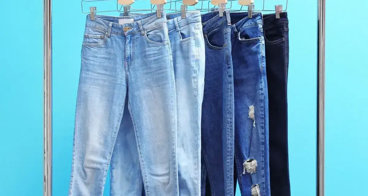 Różne modele jeansów na wieszakach. Czy rozmiar 27 spodnie damskie to Twój idealny rozmiar?