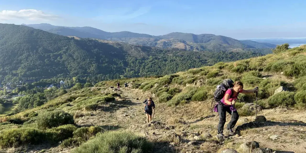 Des randonneurs progressent sur un sentier rocailleux, profitant d'une vue panoramique sur les montagnes verdoyantes lors d'une randonnée au Mont Aigoual.