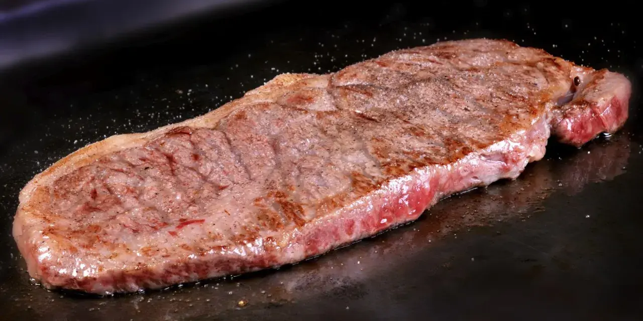 Filete de ternera jugoso cocinándose en una plancha. Perfecto para tus recetas con filetes de ternera.