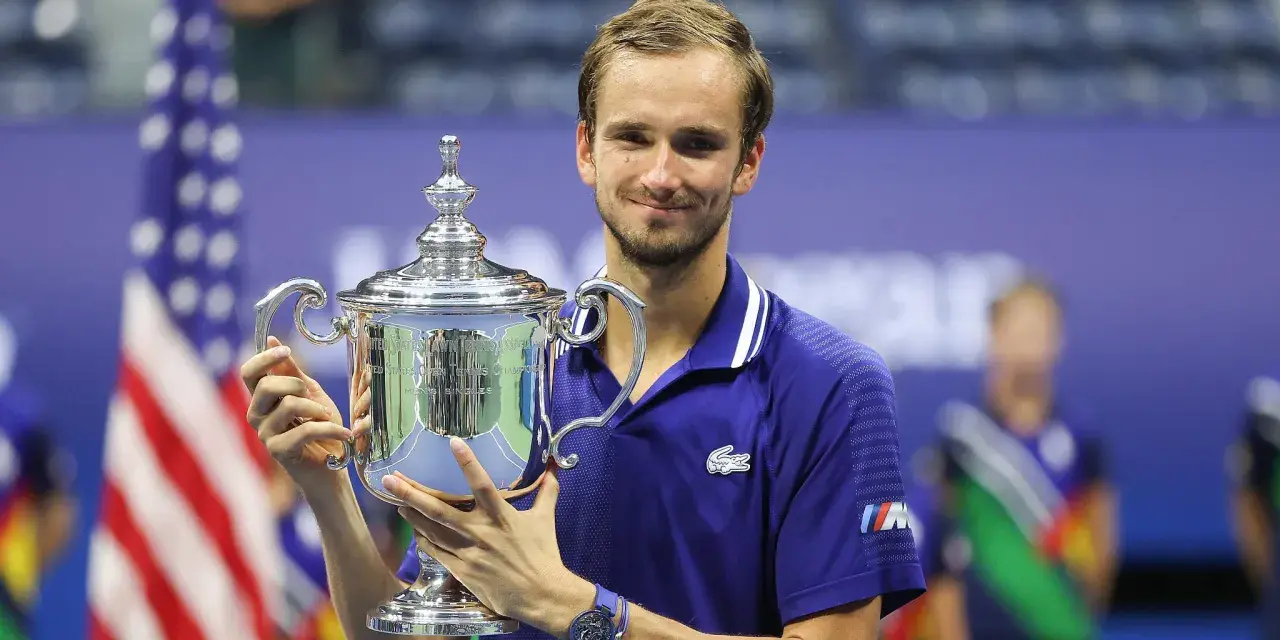 Daniil Medvedev, sonriendo, sostiene el trofeo del US Open, un logro que lo consolida entre los grandes de los medvedev grand slams.