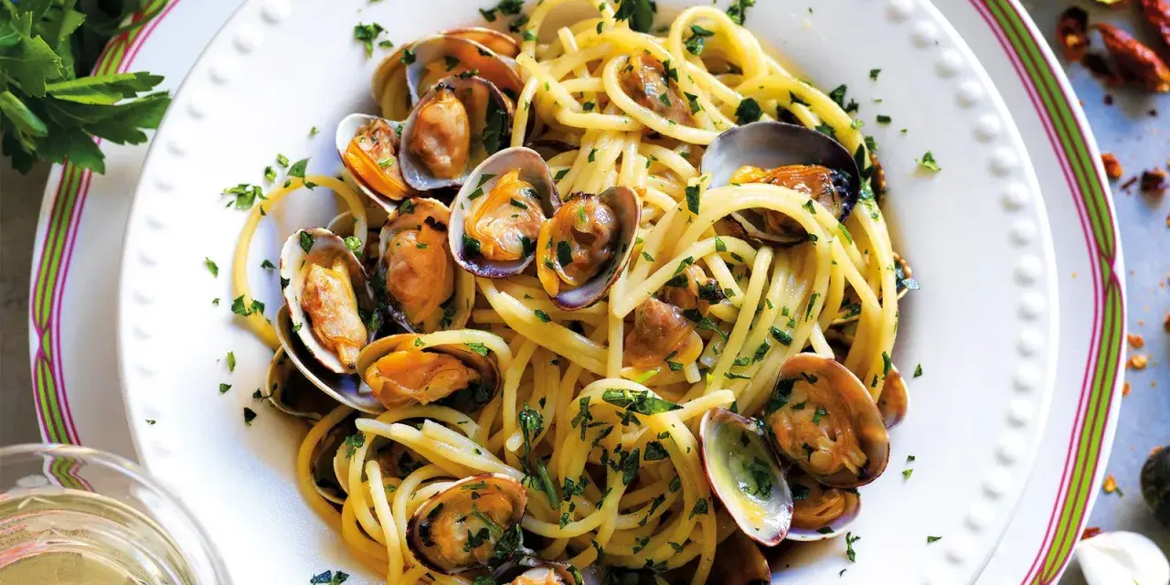 Spaghetti alle vongole surgelate, un piatto gustoso e veloce. Pasta dorata con molluschi freschi e prezzemolo tritato, pronto in pochi minuti.