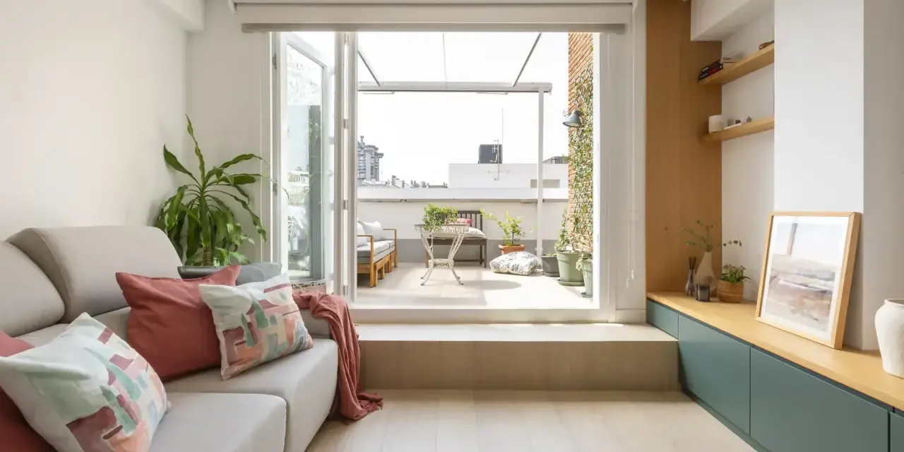Ideas para decorar un salón rectangular: sofá gris, cojines coloridos, plantas y acceso a terraza.