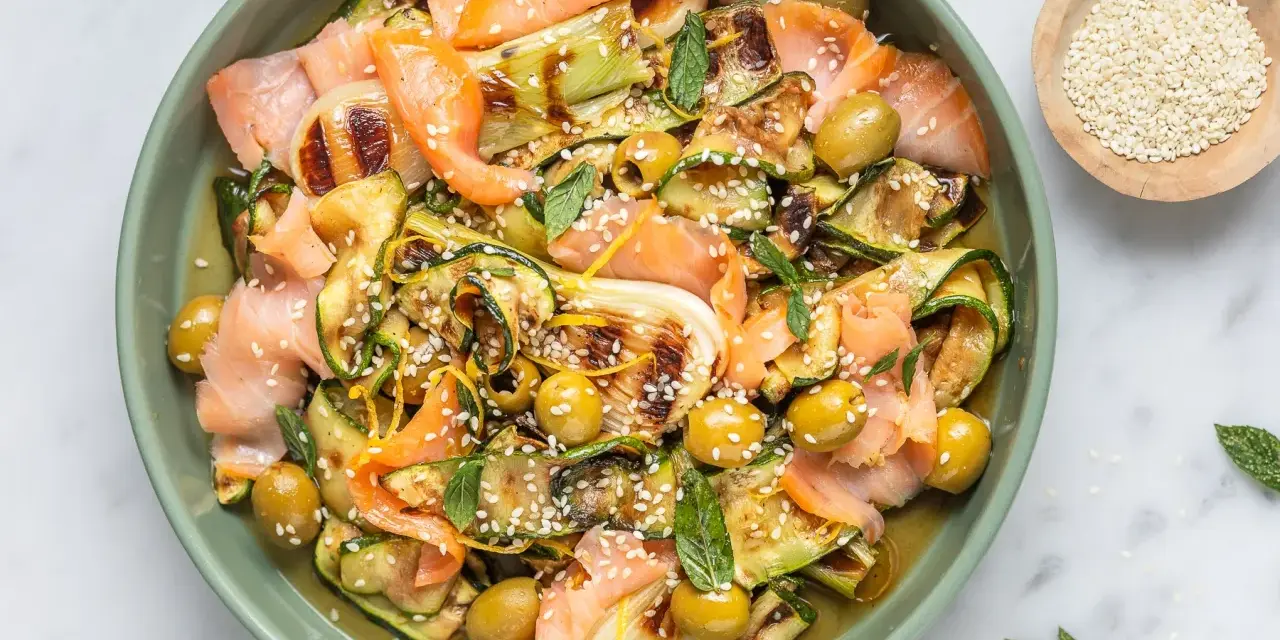 Insalata colorata con salmone affumicato, zucchine grigliate, olive e semi di sesamo. Un'idea per piatti freddi veloci e gustosi.