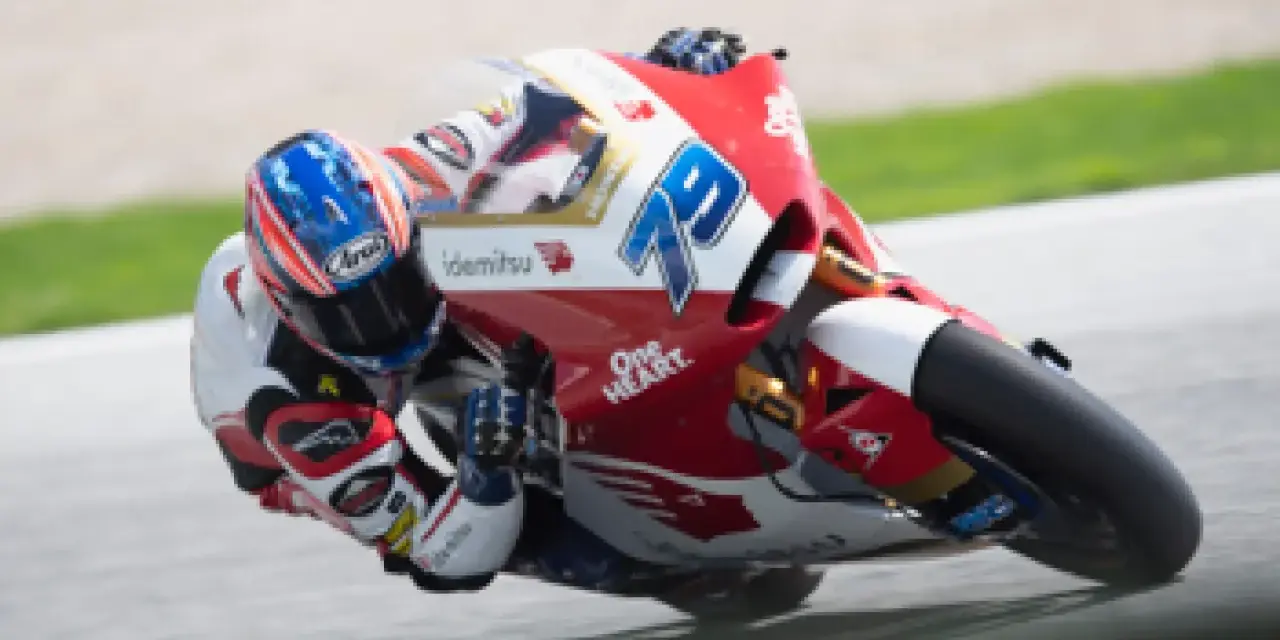Piloto en plena curva durante una carrera de moto gp. La moto roja y blanca lleva el número 79.