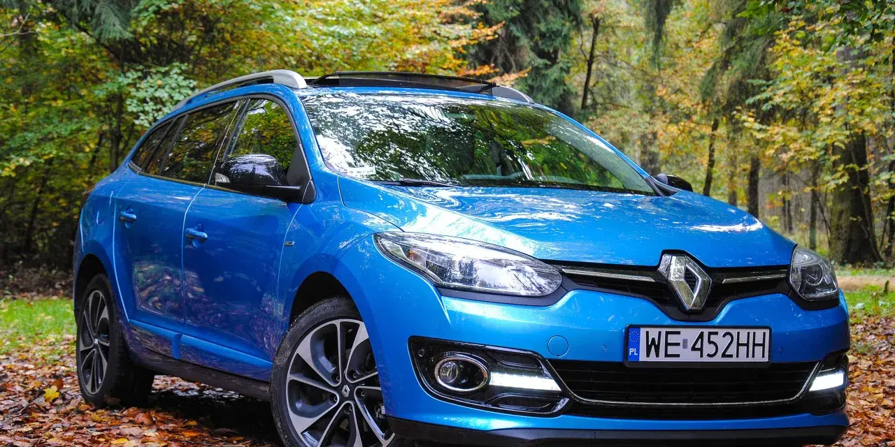 Niebieski Renault Megane 2 1.6 16v na tle jesiennego lasu.