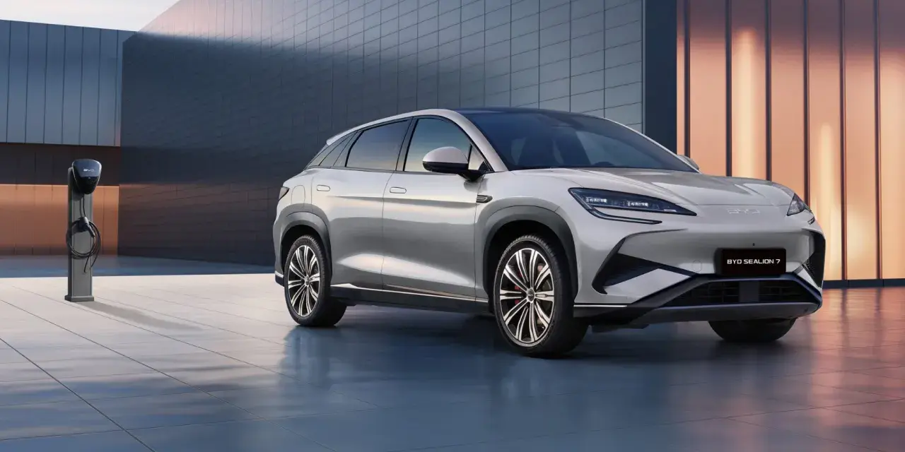 Srebrny SUV BYD Seal U stoi obok ładowarki na tle nowoczesnego budynku.